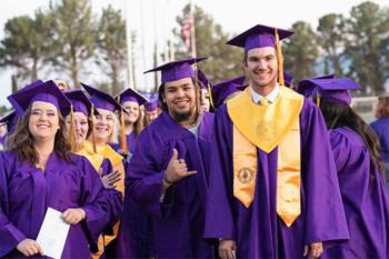 graduates in purple gowns and caps smiling outdoors