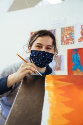 student painting on canvas in art class