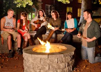 students sitting around a fire pit at night