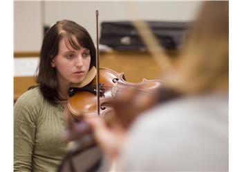 focused student playing the violin indoors