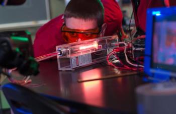 student conducting an experiment with red goggles