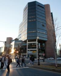 pedestrians crossing street in front of a modern building with 'massart' sign