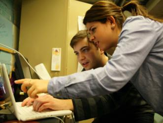 two people discussing work on a laptop