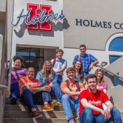 students sitting on stairs under 'holmes community college' sign