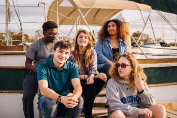 group of students sitting on a sailboat