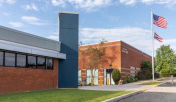 brick building with american flags and clear sky