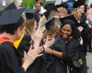 graduates hugging and clapping at commencement ceremony