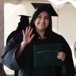 graduate in cap and gown holding a diploma with 'northwest state community college'