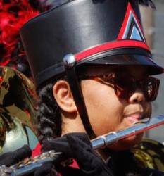 band member in uniform playing a flute with decorative hat