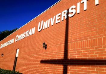 brick wall with 'southwestern christian university' and a cross shadow