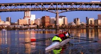two people rowing on river against cityscape