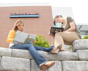two students reading on rock seating outside