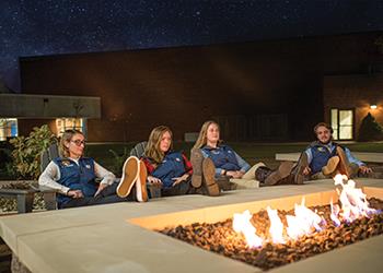 students relaxing by a fire pit at night