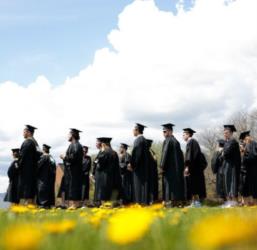 graduates in caps and gowns standing on a field