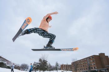 A skier performs a jumps in the air performing a trick. 