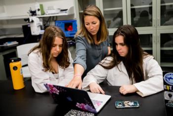 three people working together on a laptop in lab