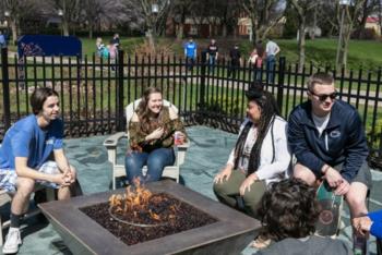 students socializing by outdoor fire pit