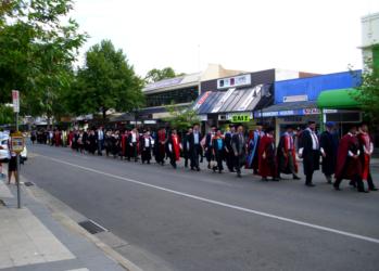 graduates in red gowns walking on street